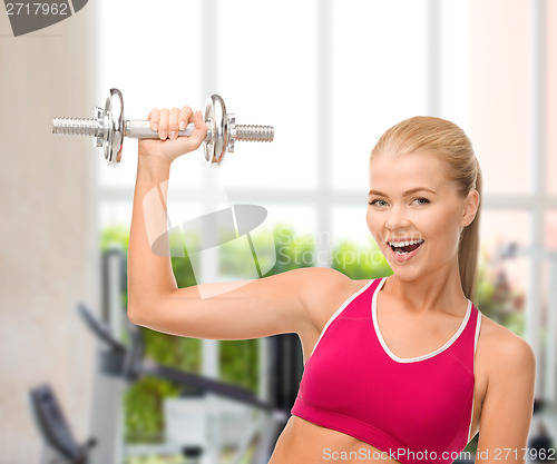 Image of smiling woman with heavy steel dumbbell