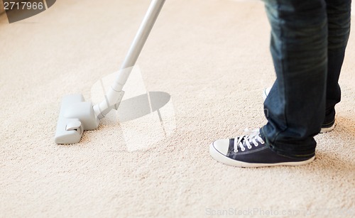 Image of close up of male hoovering carpet