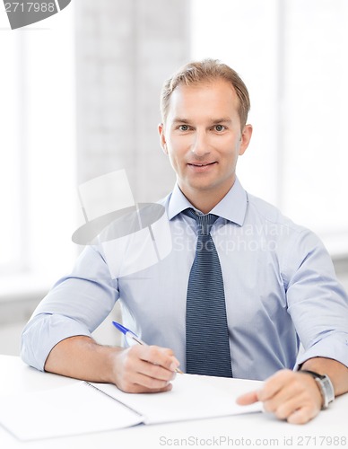 Image of handsome businessman writing in notebook