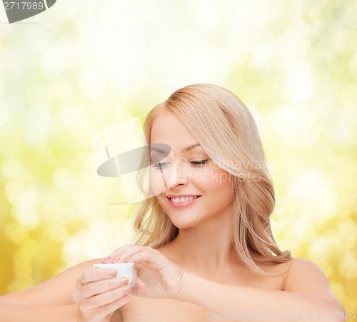 Image of beautiful woman applying cream