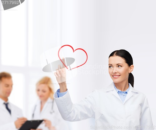 Image of smiling female doctor pointing to heart