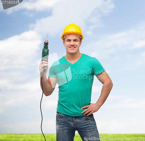 Image of smiling manual worker in helmet with drill machine