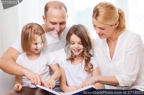 Image of smiling family and two little girls with book