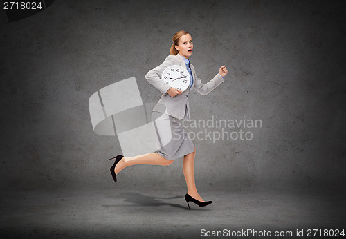 Image of stressed young businesswoman with clock running