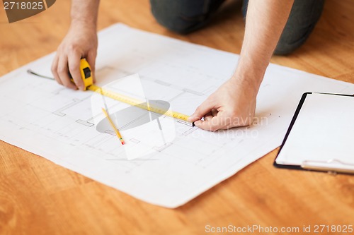 Image of close up of male hands measuring blueprint