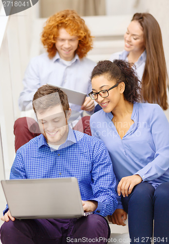 Image of team with laptop and tablet pc on staircase