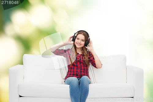 Image of teenage girl sitting on sofa with headphones