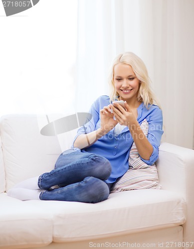 Image of smiling woman with smartphone at home