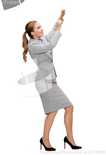 Image of smiling businesswoman pulling imaginary rope