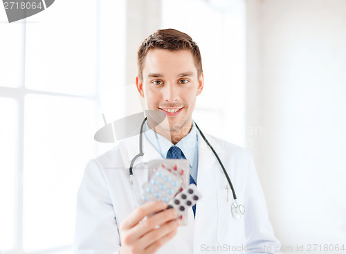 Image of smiling male doctor with pills in hospital