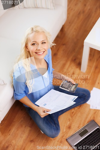 Image of smiling woman with papers, laptop and calculator