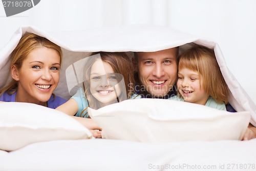 Image of happy family with two kids under blanket at home