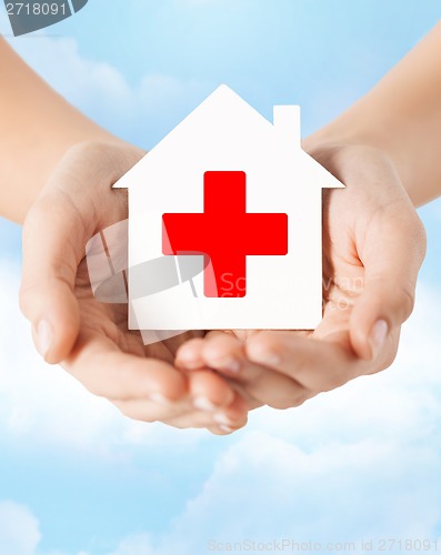 Image of hands holding paper house with red cross