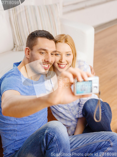 Image of smiling couple taking picture with digital camera