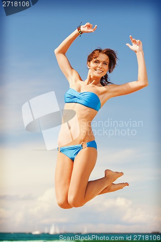 Image of happy jumping woman on the beach