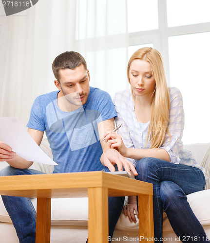 Image of busy couple with papers and calculator at home