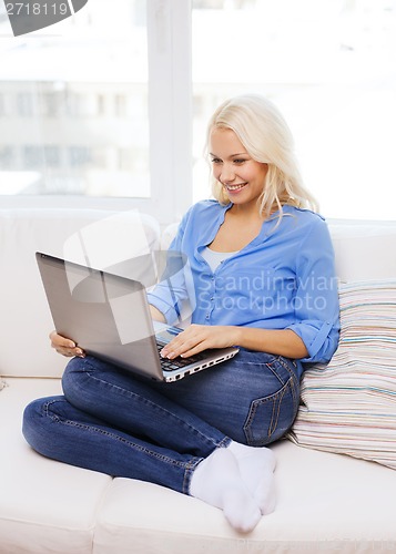 Image of smiling woman with laptop computer at home
