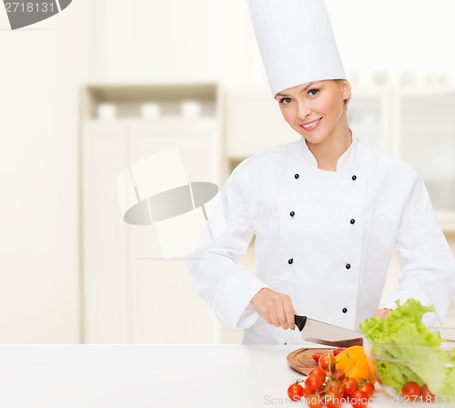 Image of smiling female chef chopping vagetables