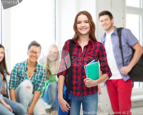 Image of smiling female student with bag and notebooks