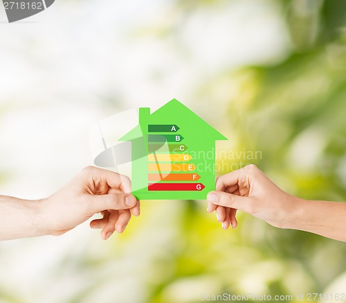 Image of hands holding green paper house