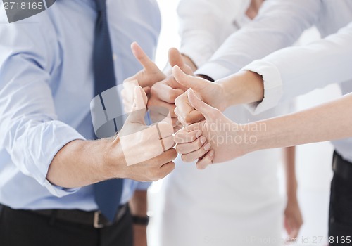 Image of business team showing thumbs up in office