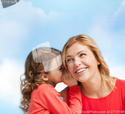 Image of smiling mother and daughter whispering gossip