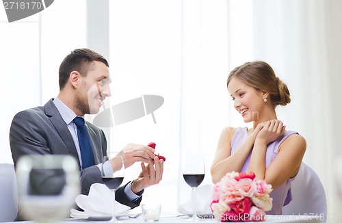 Image of man proposing to his girlfriend at restaurant