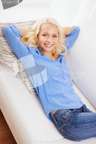 Image of smiling young woman lying on sofa at home