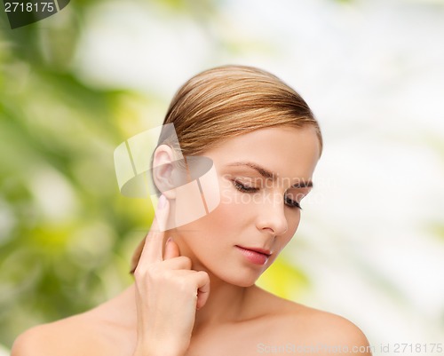 Image of calm woman touching her ear