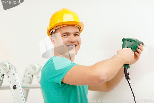 Image of man with electric drill making hole in wall