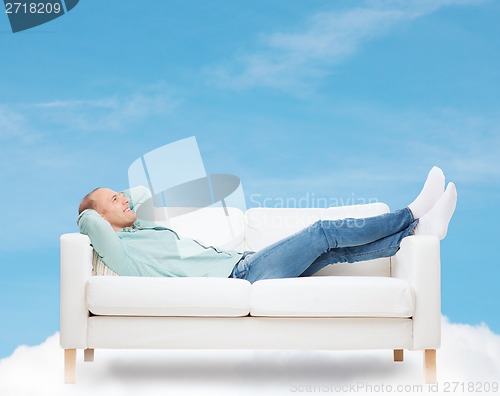 Image of smiling man lying on sofa