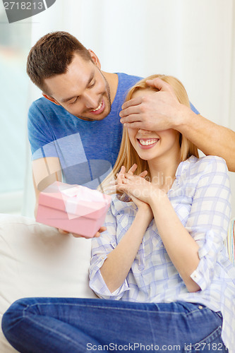 Image of smiling man surprises his girlfriend with present