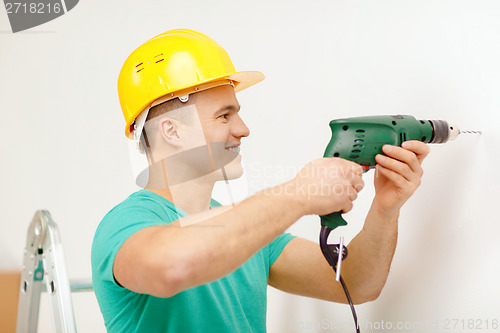 Image of man with electric drill making hole in wall