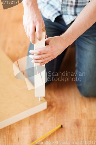 Image of close up of male hands assemblying legs to table