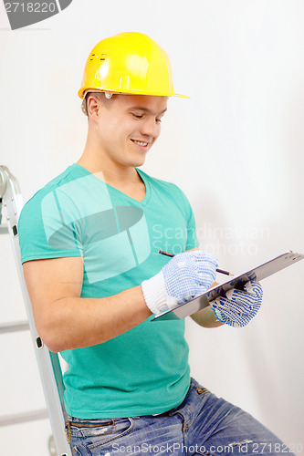 Image of smiling man in protective helmet with clipboard