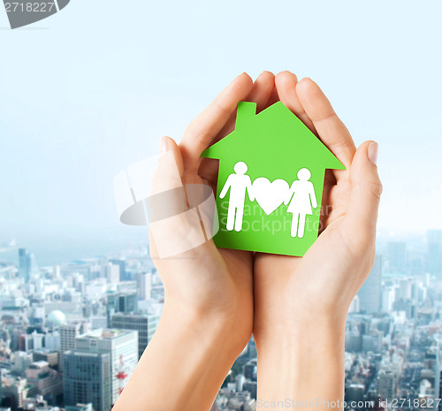 Image of hands holding green house with family