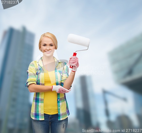 Image of smiling woman in gloves with paint roller