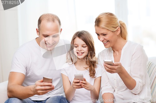 Image of parents and little girl with smartphones at home