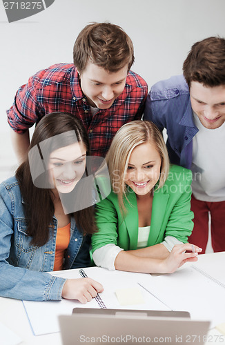 Image of smiling students looking at laptop at school