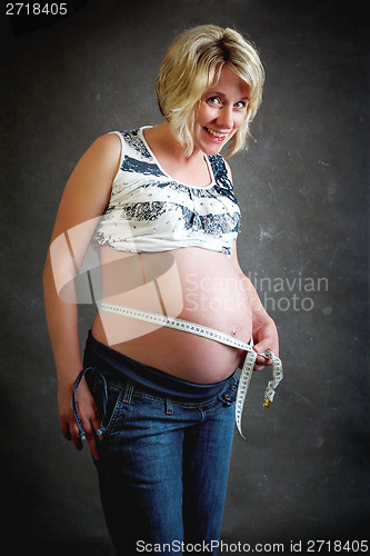 Image of beautiful pregnant woman tenderly measuring her tummy