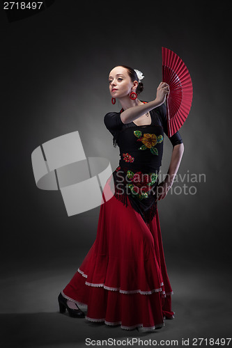 Image of young woman dancing flamenco with fan on black