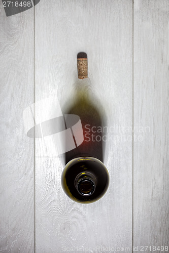 Image of Bottle of red wine with cork on white wooden table. Top view