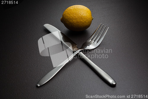 Image of lemon with crossed knife and fork on black