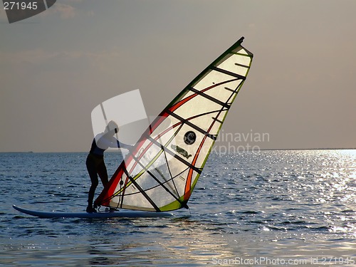Image of A women is learning windsurfing at the sunset