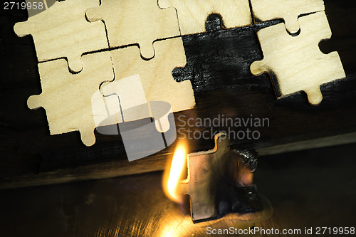 Image of Burning wooden puzzle on dark background.