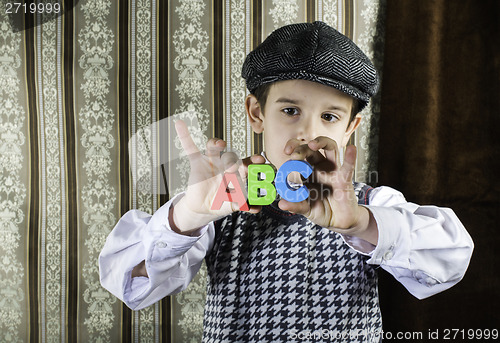 Image of Child in vintage clothes hold letters a b c