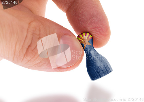 Image of Hand holding wooden pawn, flag painting, selective focus