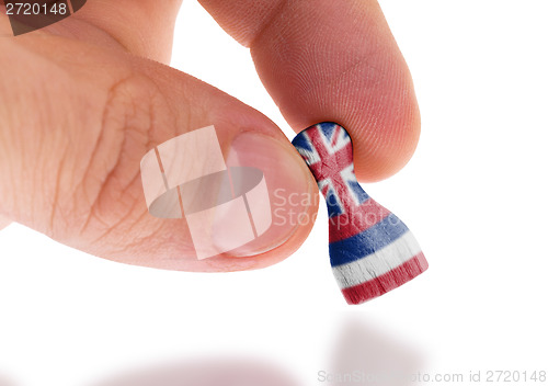 Image of Hand holding wooden pawn, flag painting, selective focus