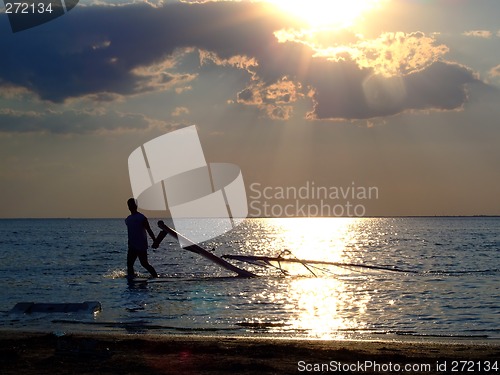 Image of The guy drags the windsurf on a sunset