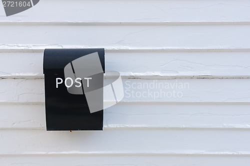 Image of Black mail box on the traditional white wooden wall of house